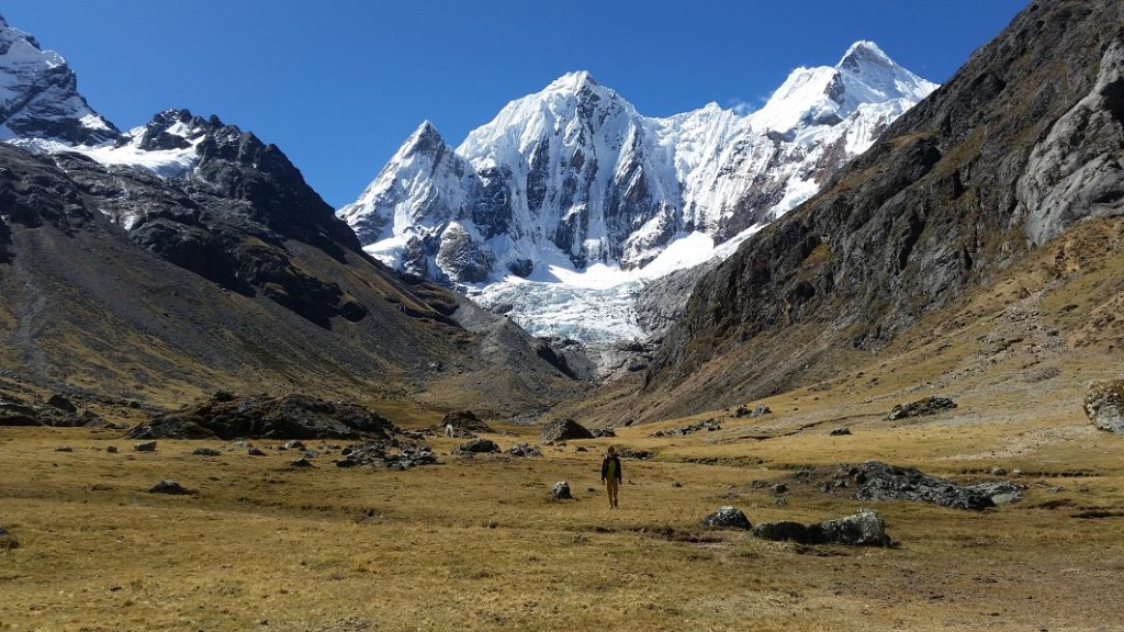 Séjour de Trekking au Pérou. Un homme pratique la randonnée au milieu d'un champ avec des montagnes enneigées en arrière-plan.