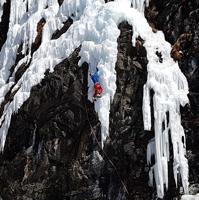 Séjour d'Escalade sur cascade de glace. Un homme cramponné à un bloc de glace au bord d'une paroi rocheuse. 