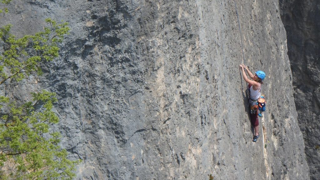 Séjour d'escalade en falaise dans la Jonte. Une femme escalade une paroi 