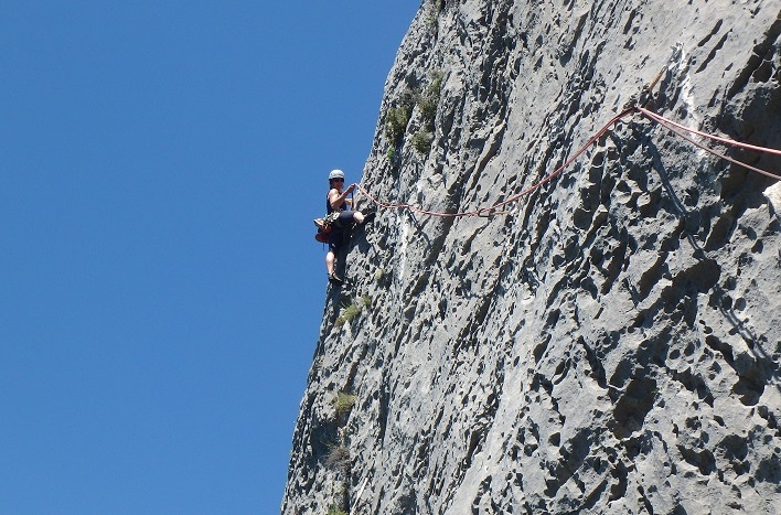 Une femme encordée grimpe une falaise dans les Gorges du Verdon, une destination d'escalade idéale pour un stage